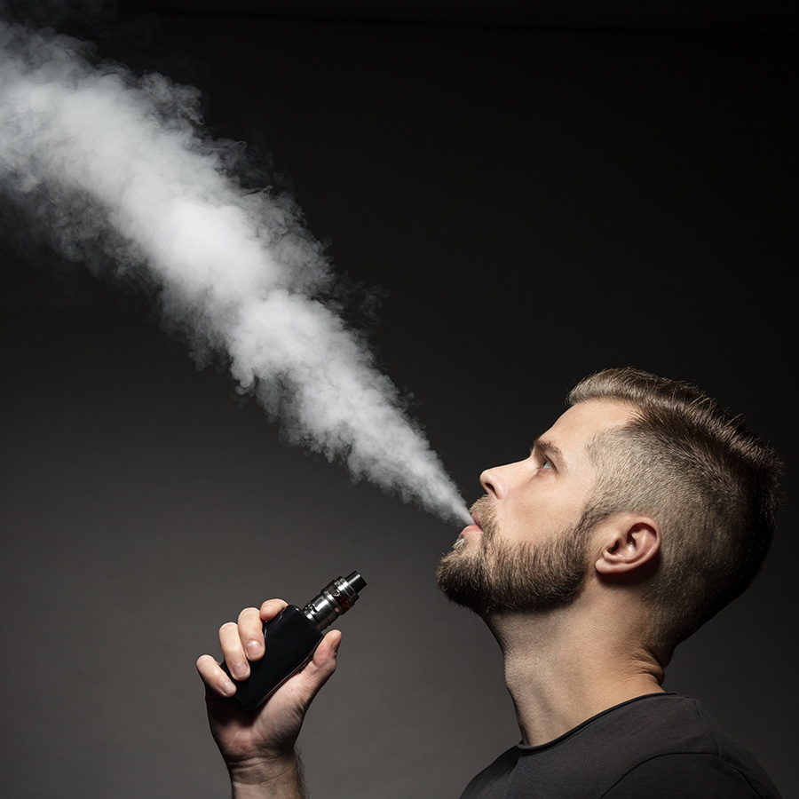 Adult using vape device producing vapor cloud – Los Angeles vape shop products